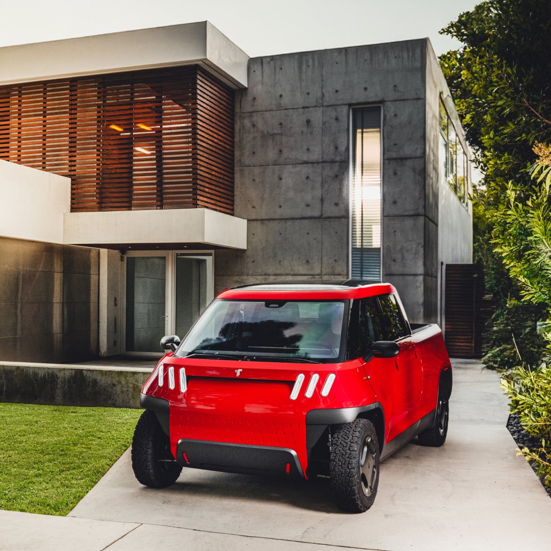 Red electric SUV parked in front of modern house with large windows