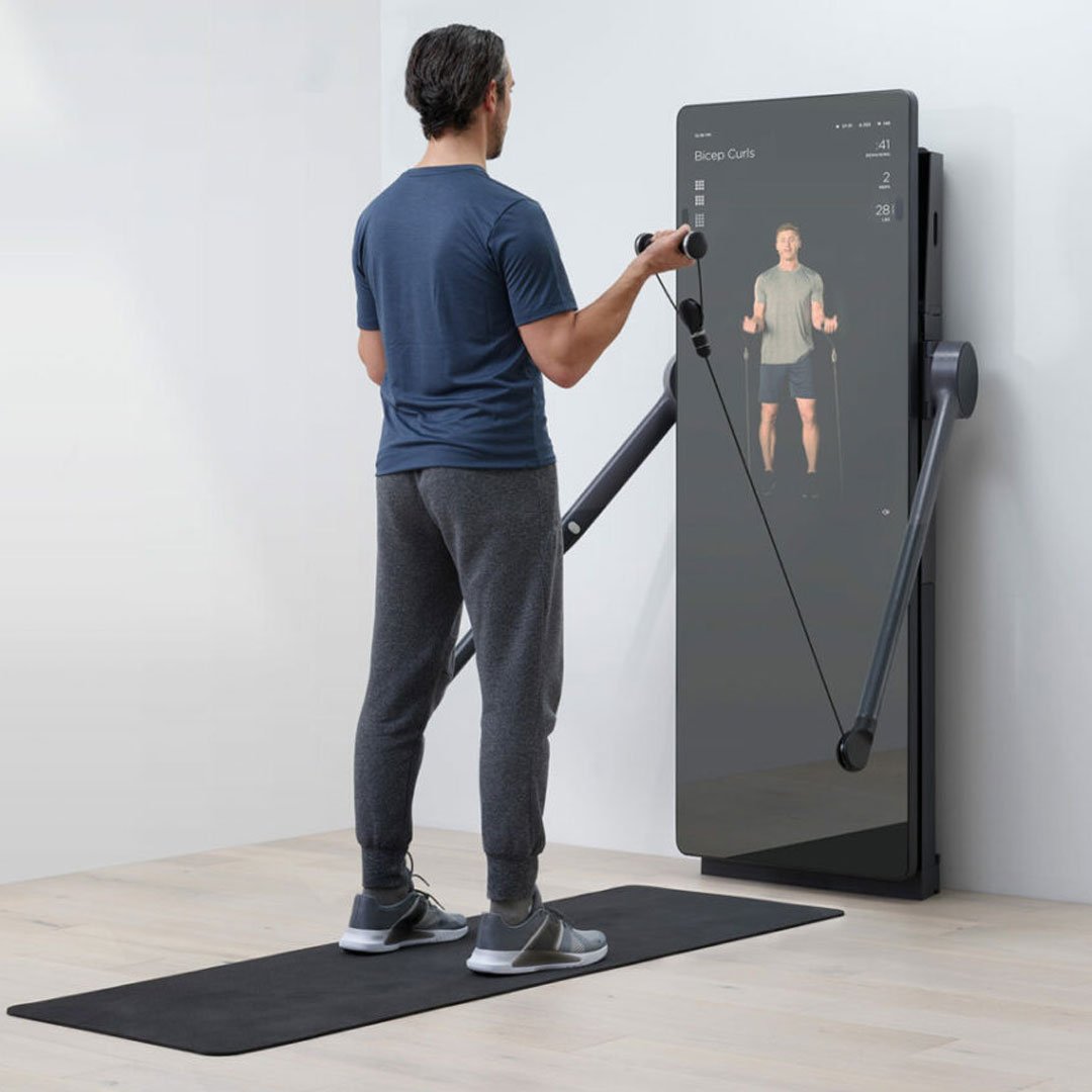Man interacting with a touch screen and standing near an exercise machine