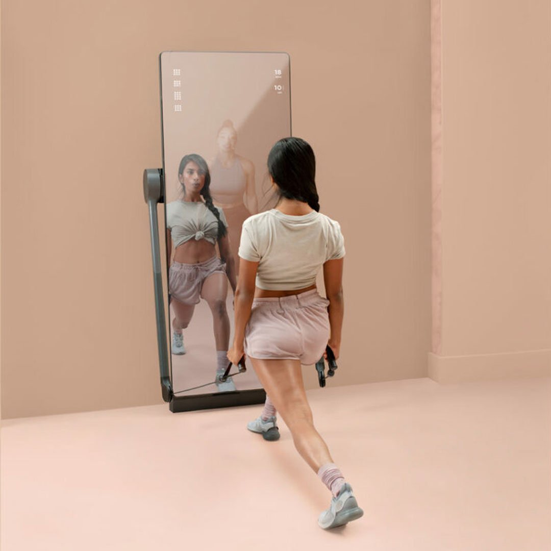Two women exercising in front of mirrors with water bottles behind them