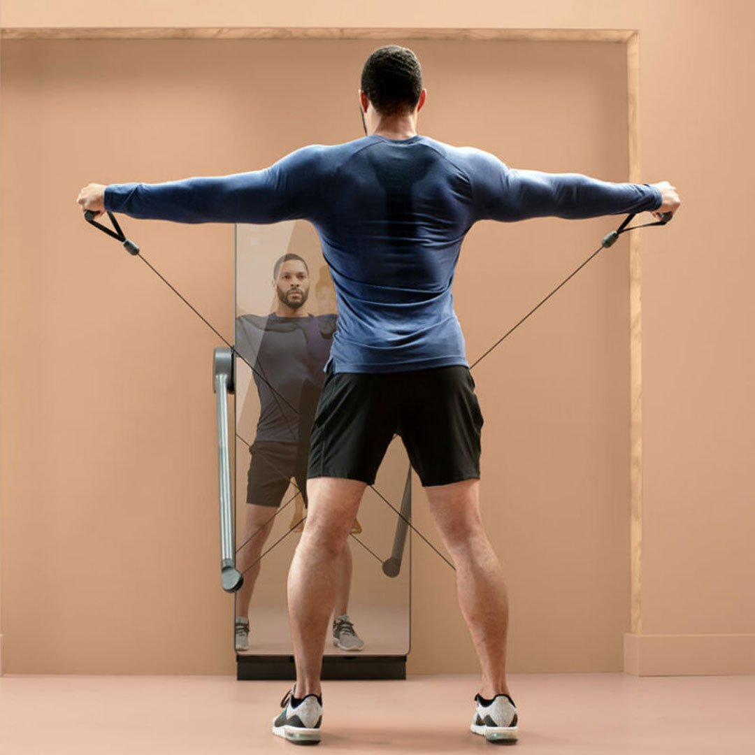 Man in blue tank top and black shorts using a cable machine