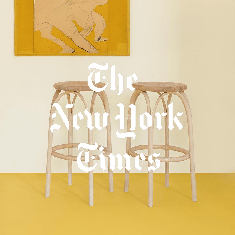 Yellow background with two wooden stools and a small table, overlaid with