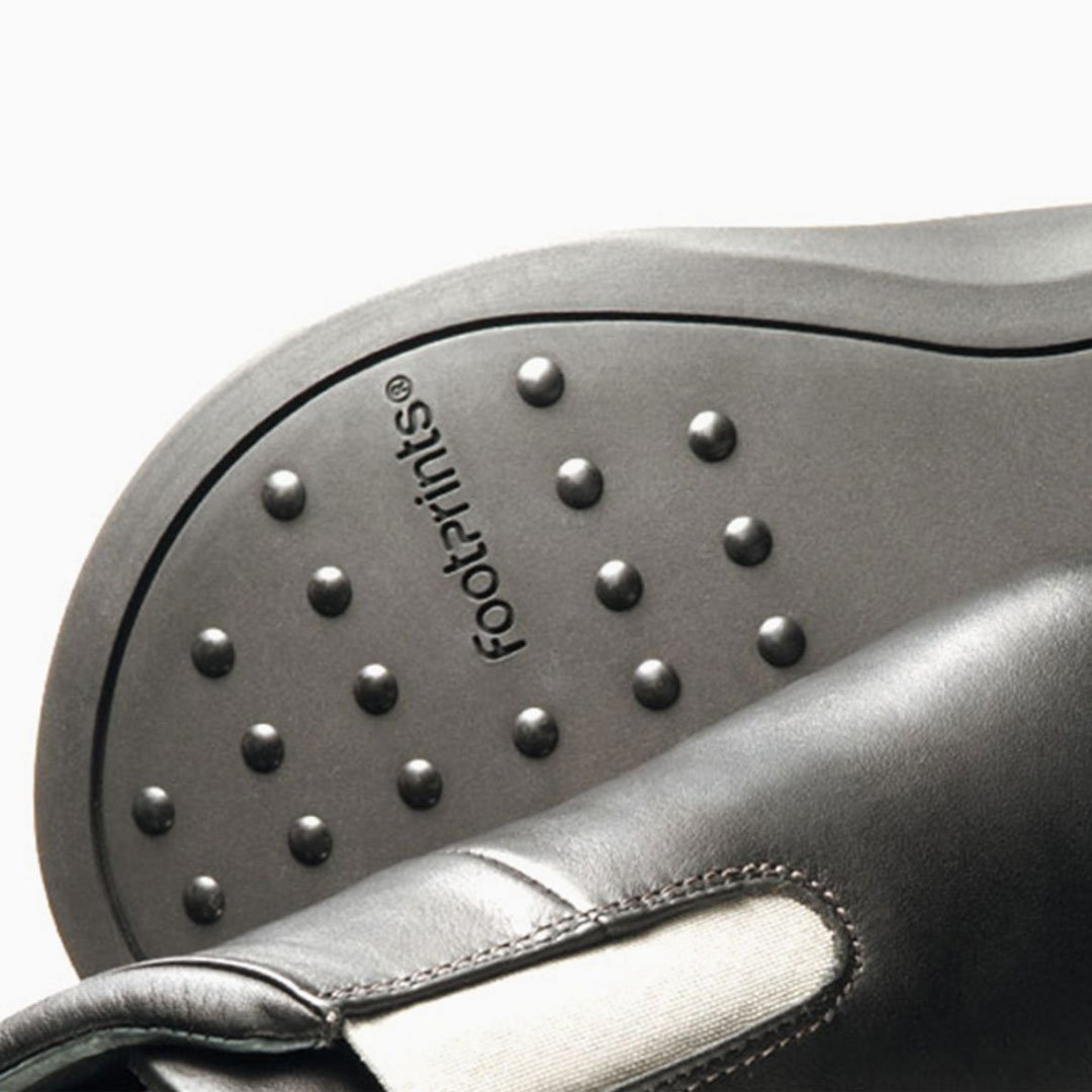 Black sandals with textured soles and circular studs on a white background