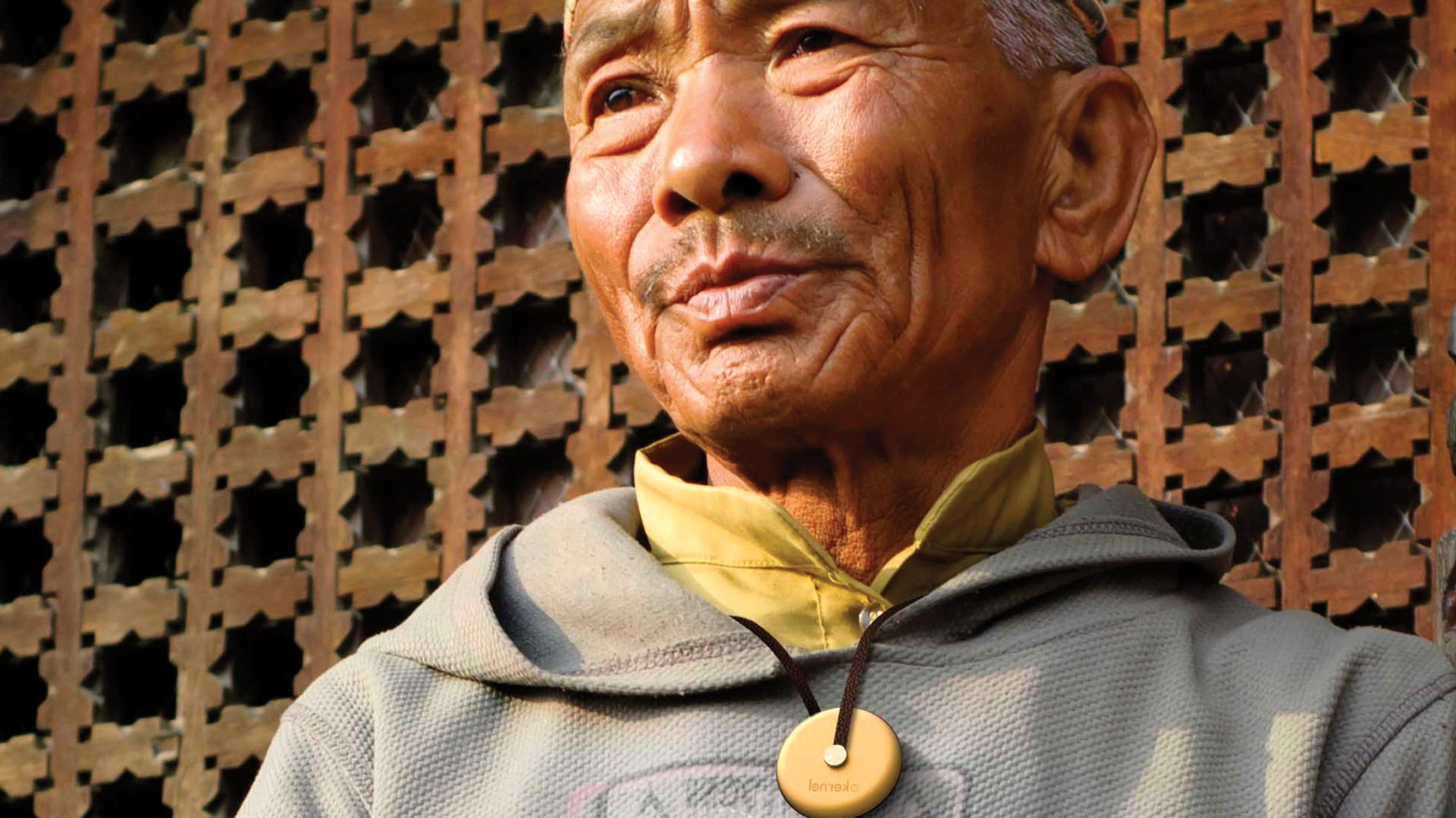 Kernel project portrait of an elderly man with mustache wearing traditional Asian garment against a rustic brick wall