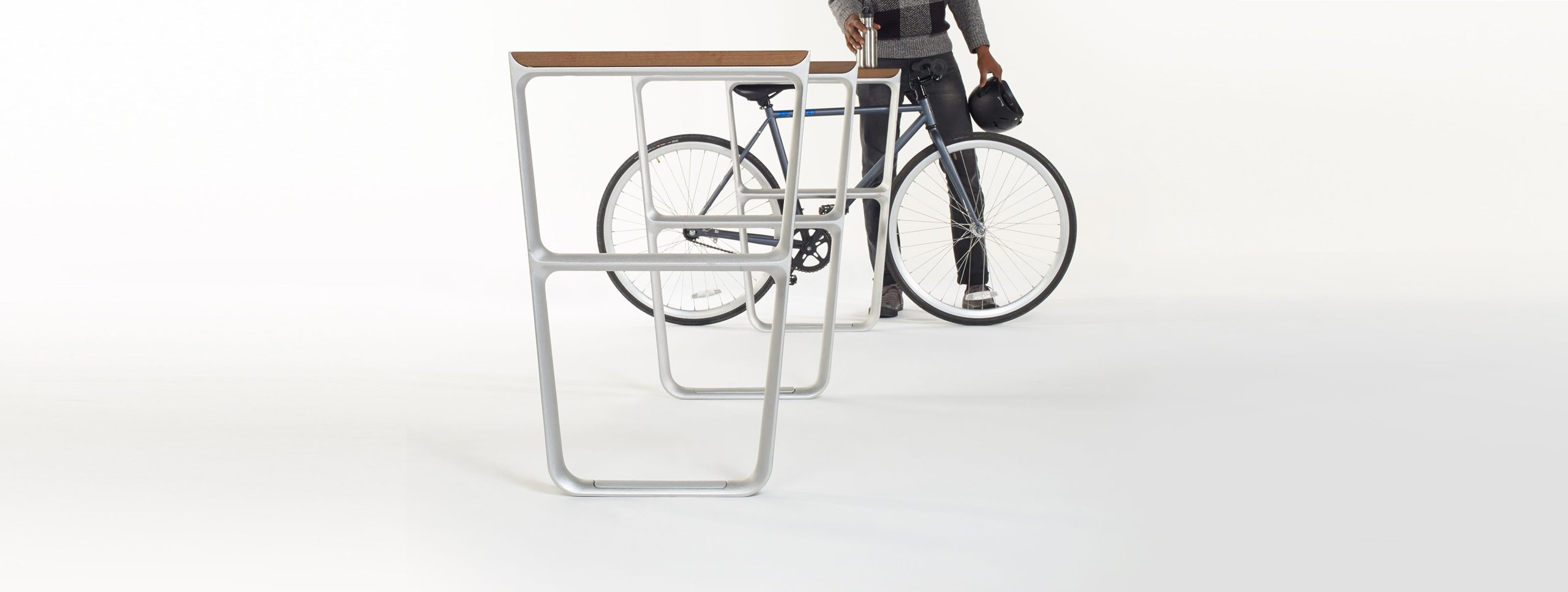 Black bicycle with silver accents leaning against a white metal rack