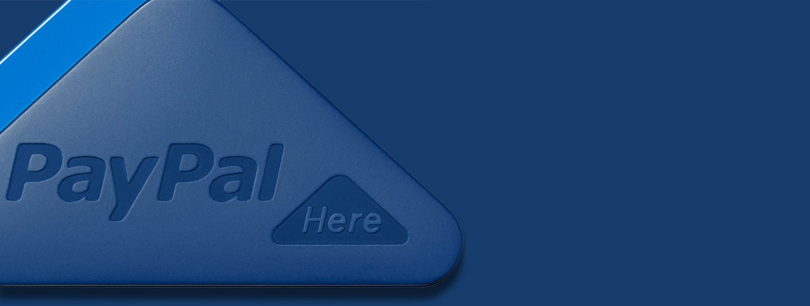 Close-up macro of PayPal Here mobile card reader, blue triangular device with embossed PayPal Here branding.