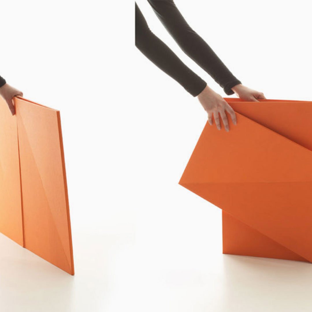 Orange cardboard box being folded into a paper airplane