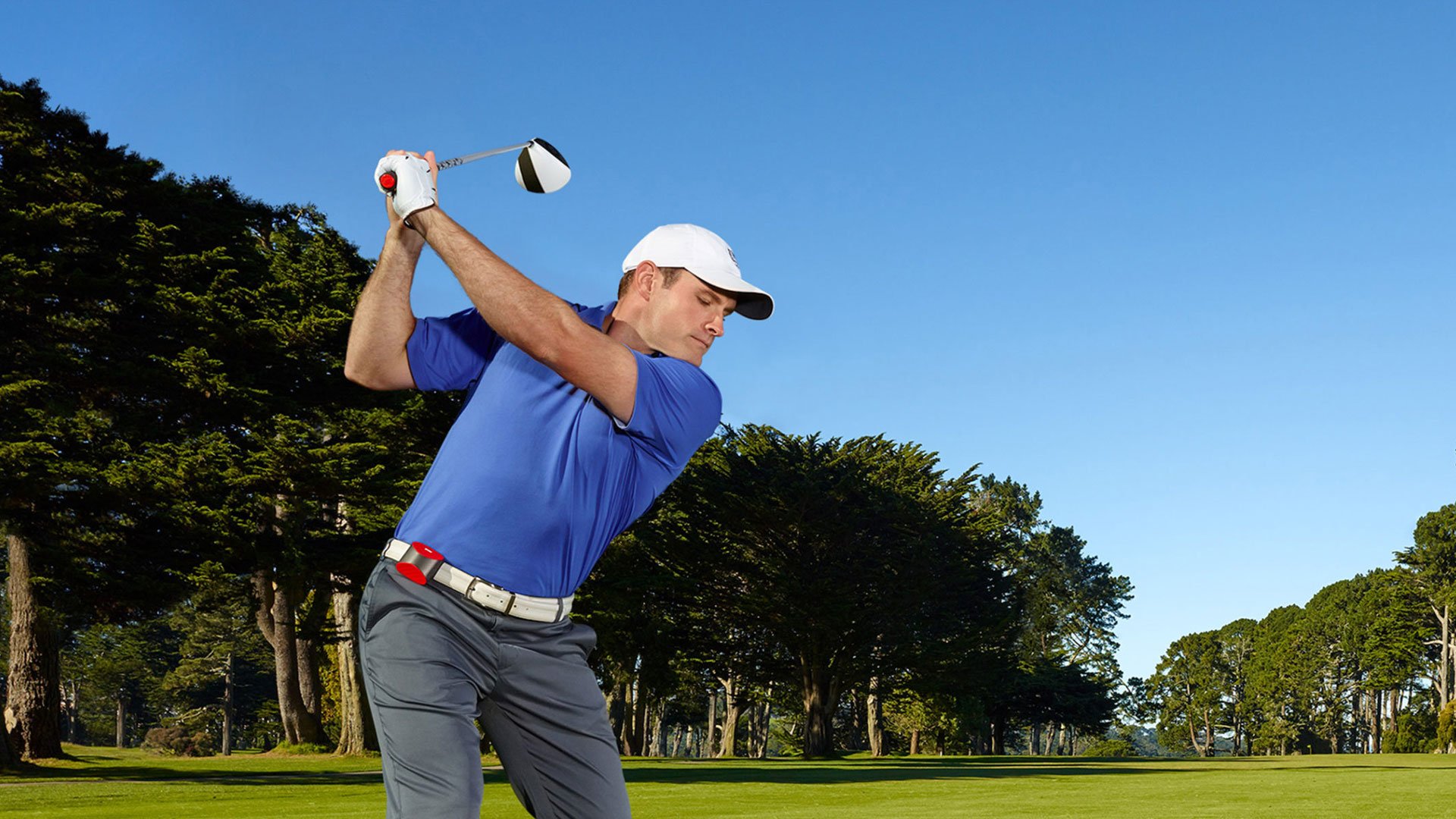 Man in blue shirt with white sleeves and red belt on a golf course