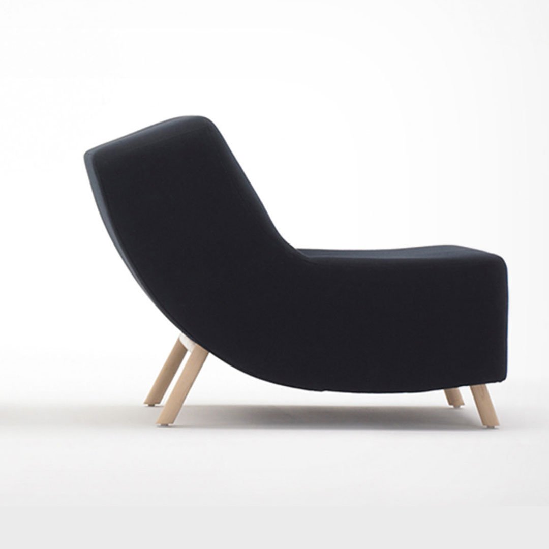 Dark blue velvet armchair with wooden legs on a plain white background