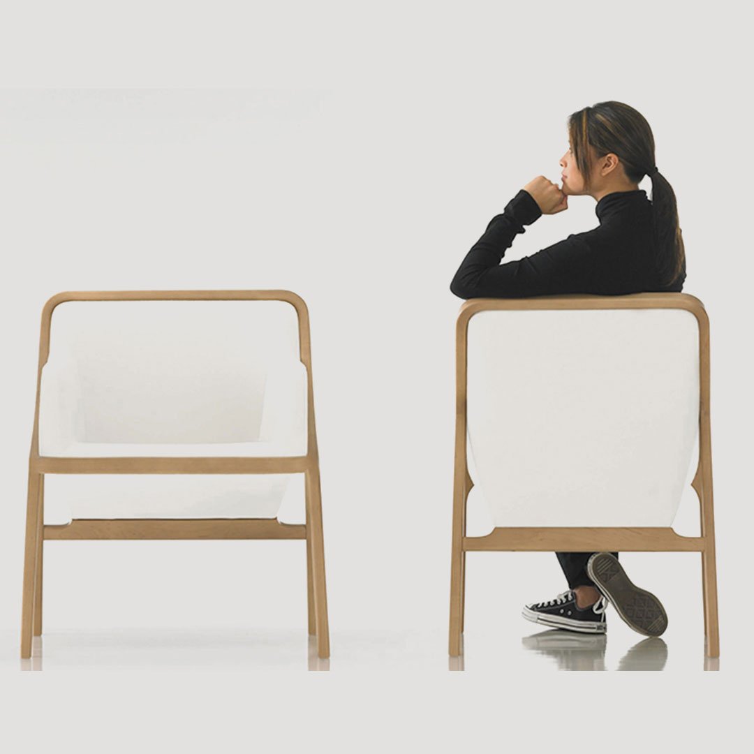 HBF person seated between two light-colored minimalist chairs in a contemporary room