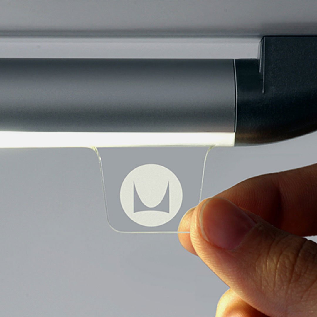 Hand holding transparent object with stylized letter 'M' logo
