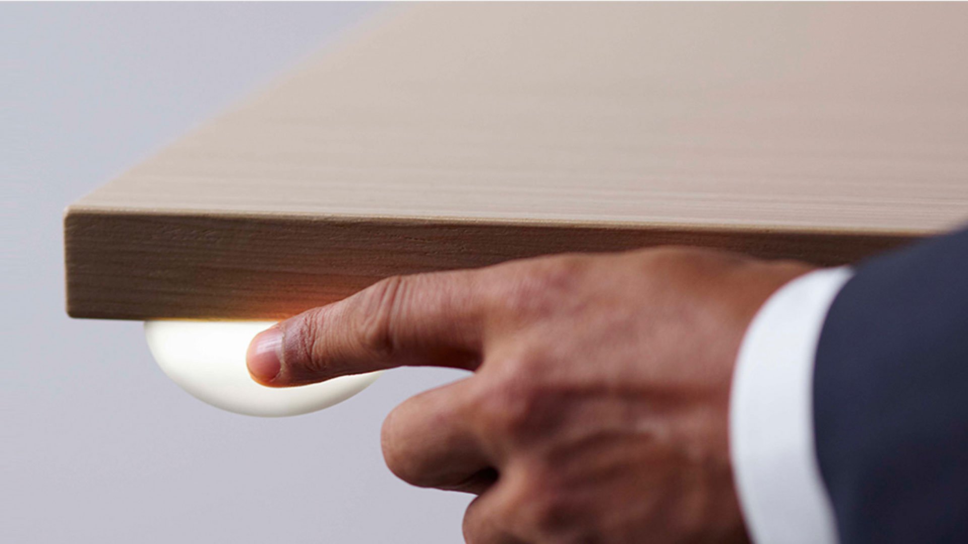 Man holding smartphone with screen lit in front of wooden table