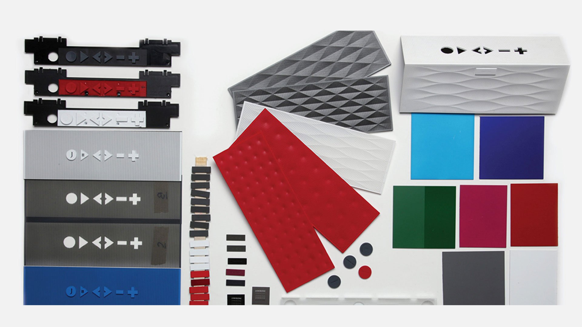 Big Jambox material exploration flat lay with button assemblies, faceted speaker grilles, red dimpled rubber samples and colo