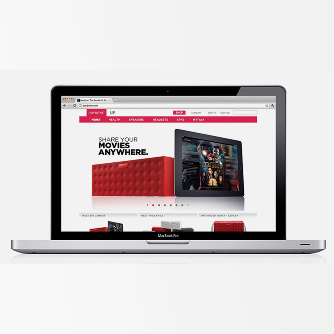 MacBook Pro displaying Jawbone.com homepage with "Share Your Movies Anywhere" Big Jambox campaign and iPad showing movie cont