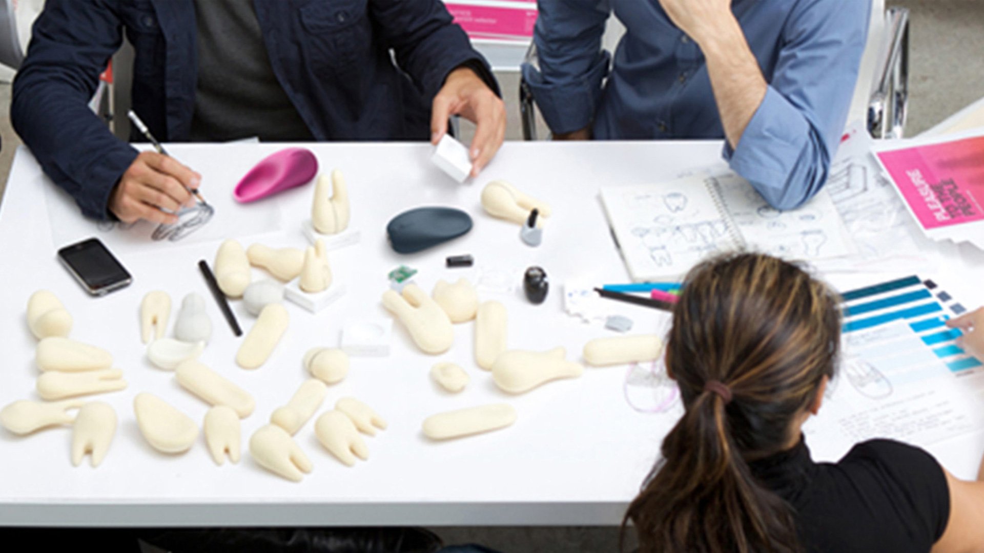 Jimmy Jane design team collaborating around a cluttered table with clay models and prototyping tools