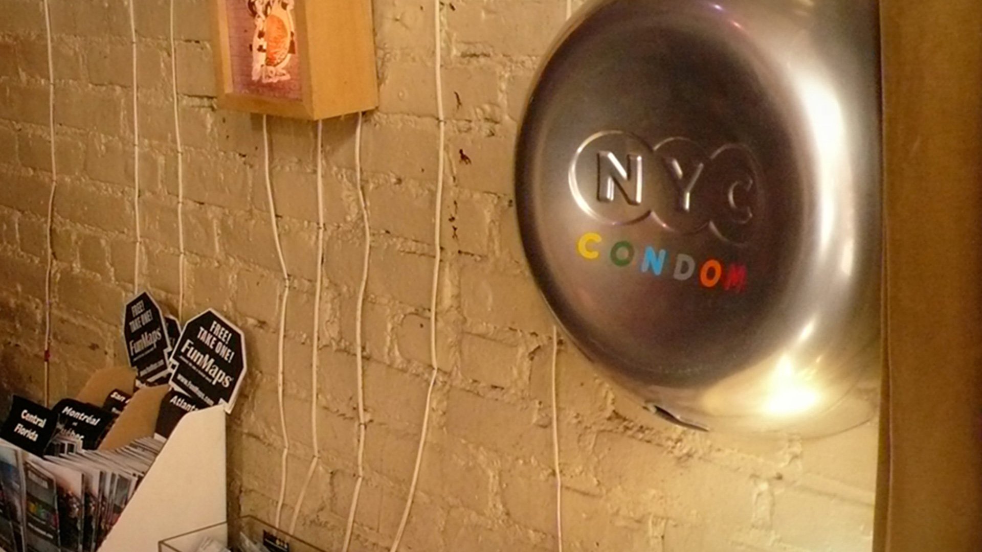 NYC Condom NYC Comedy themed display with gold and brown brick wall featuring NYC Comedy signage