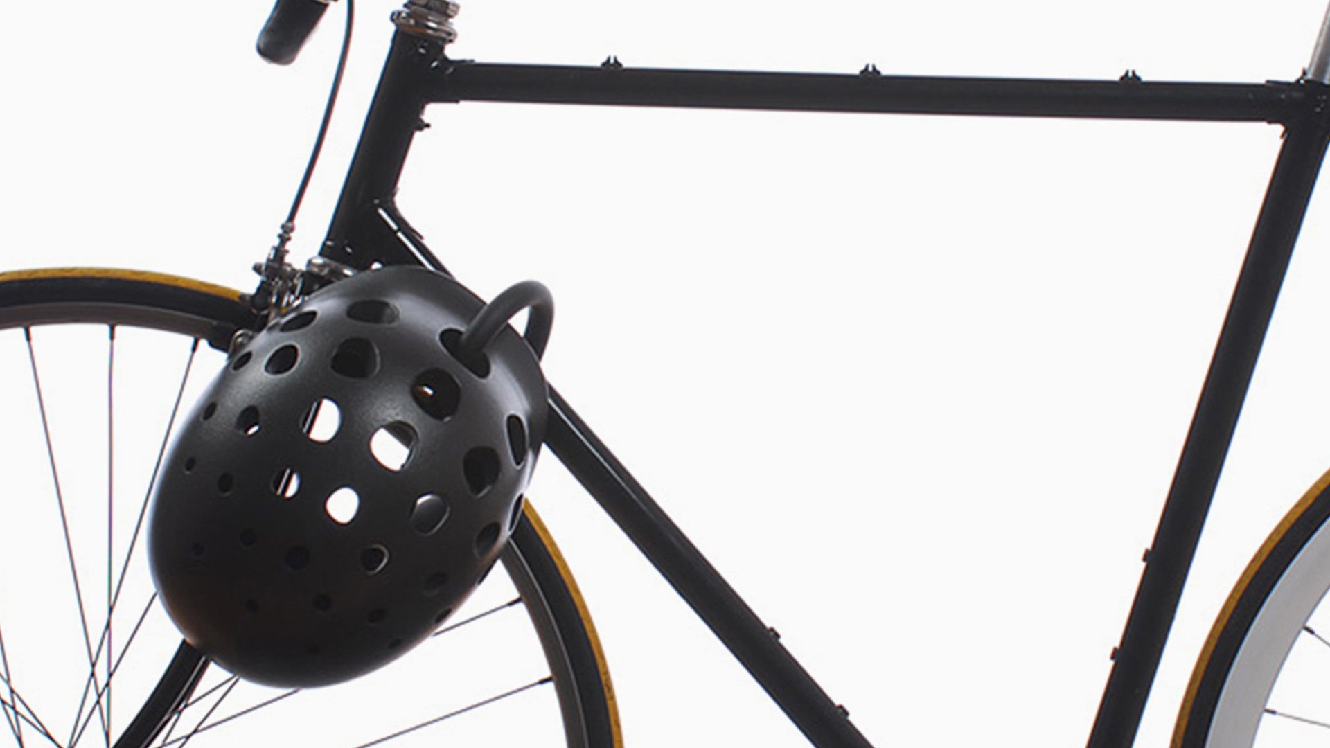 NYC Helmet shown hanging on handlebars of a black bicycle with bright yellow saddle
