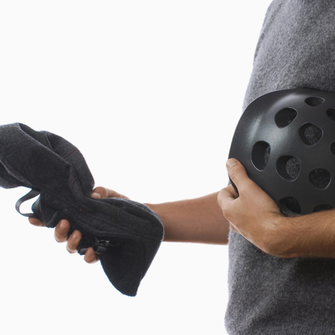 NYC Helmet design close-up: person holding a black bicycle helmet with patterned ventilation holes indoors