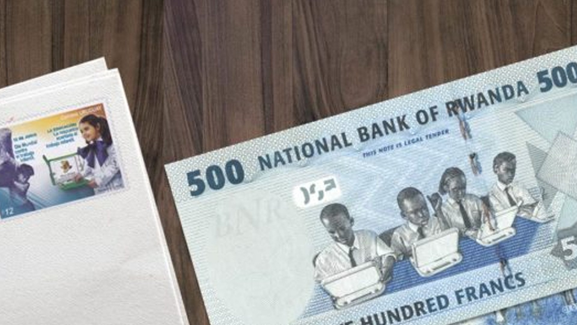 Two banknotes on a surface with paper in between, featuring Rwandan currency