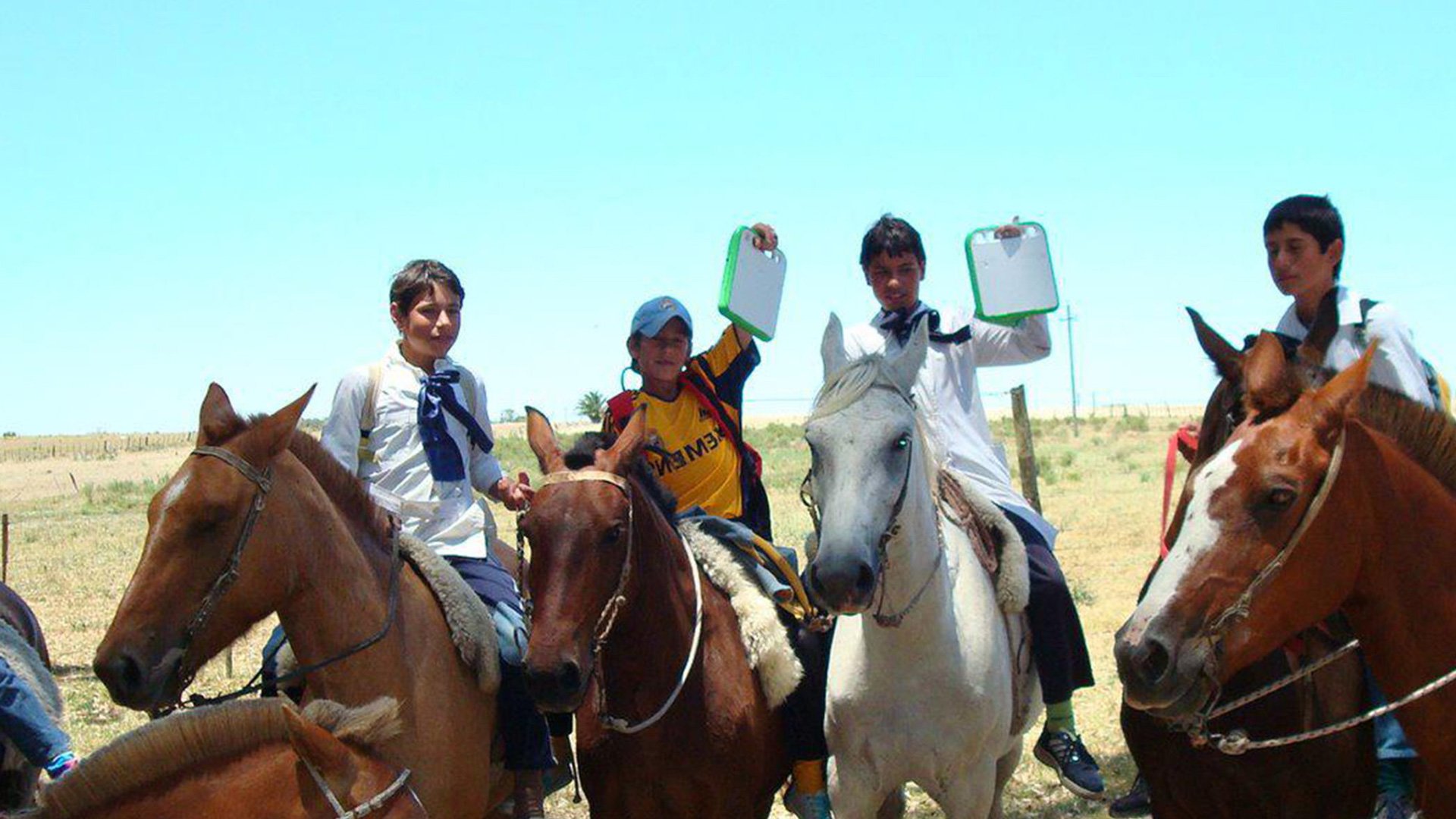 OLPC XO Laptop delivery: group of people standing outdoors with horses in a rural setting