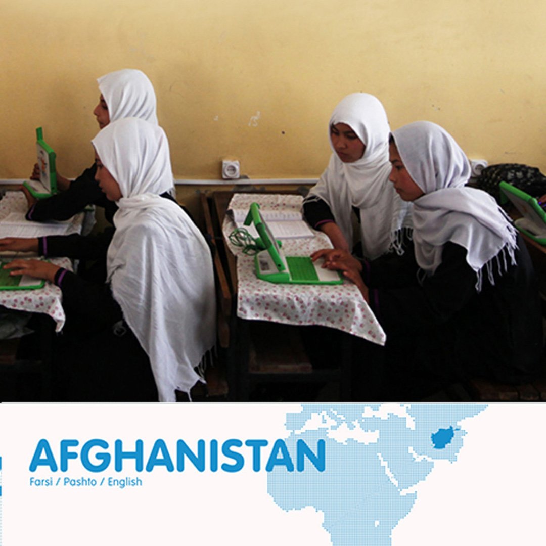 Schoolgirls in white hijabs use green OLPC XO laptops in an Afghan classroom, with Afghanistan map graphic and Farsi, Pashto,