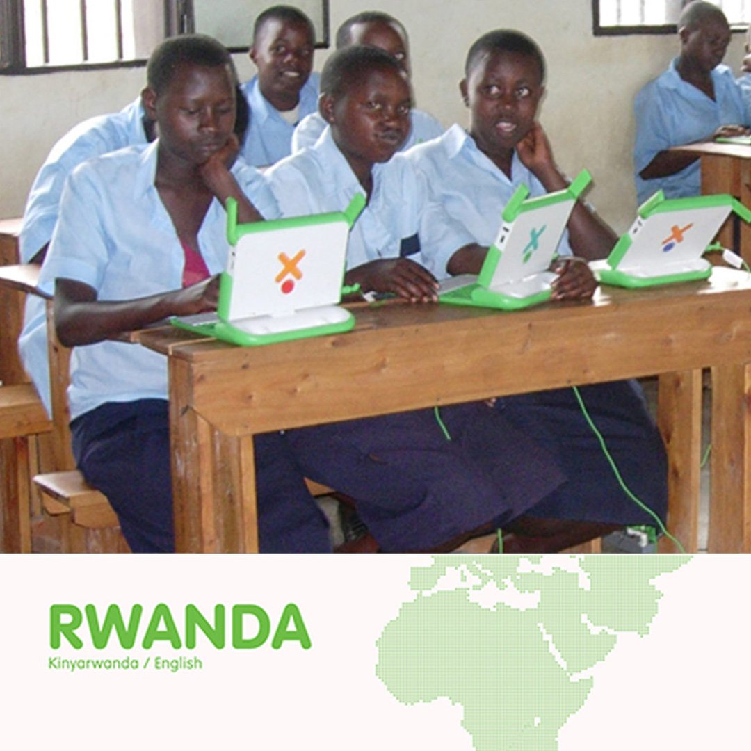 OLPC XO Laptop in Rwanda: students using green XO laptops in a classroom with a Kinyarwanda English sign