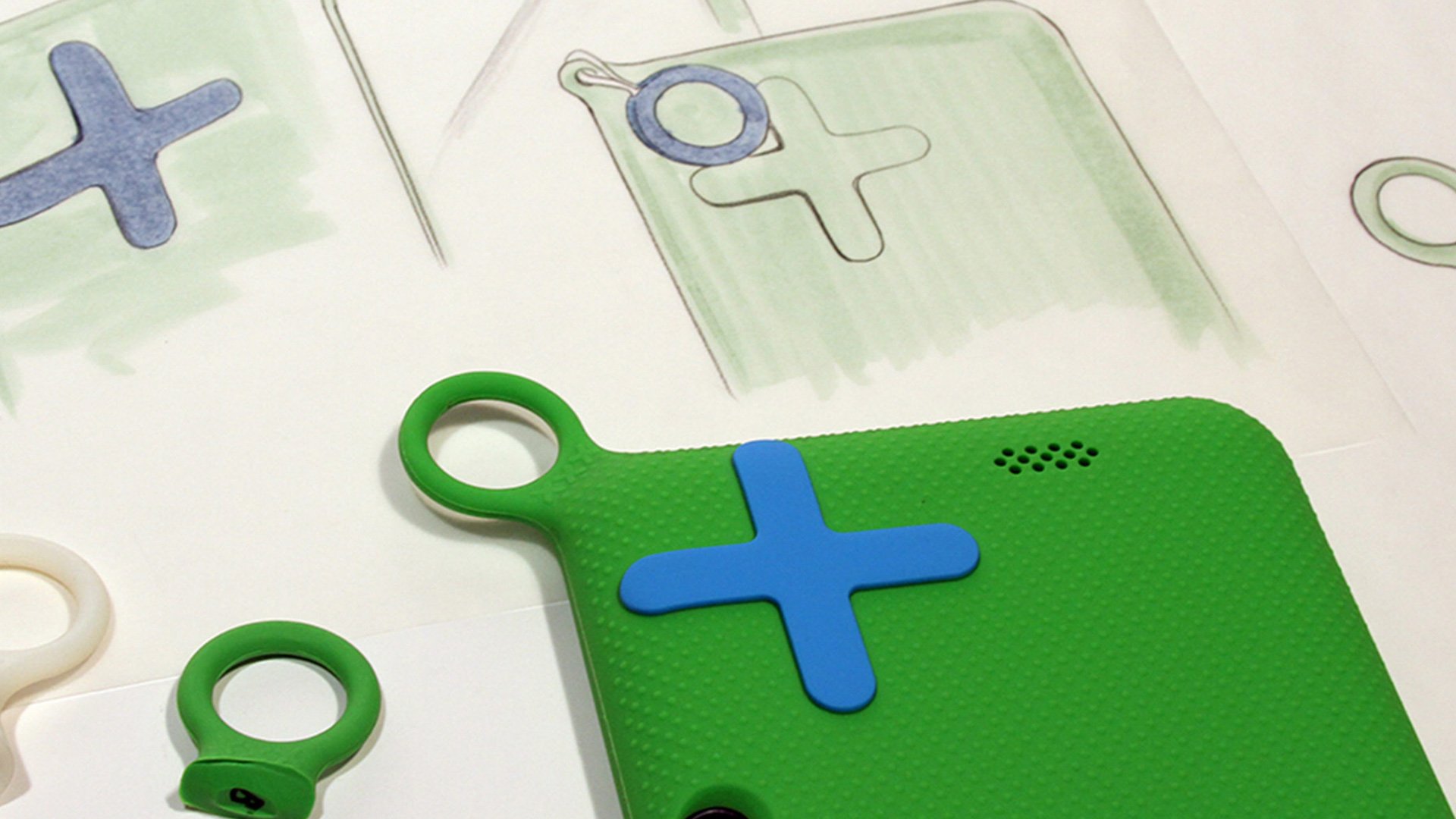 OLPC XO Tablet design components: colorful plastic shapes and parts with blue cross symbol on a workspace