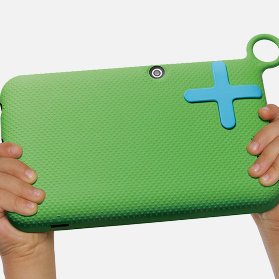 Back of OLPC XO green child-friendly tablet held by small hands, featuring textured rubber casing, blue plus-shaped button, c