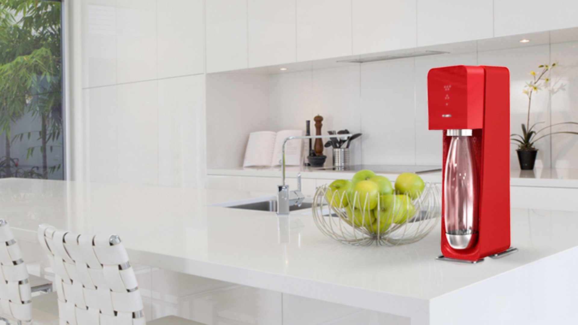 Red coffee machine on modern kitchen counter with fruit and vase