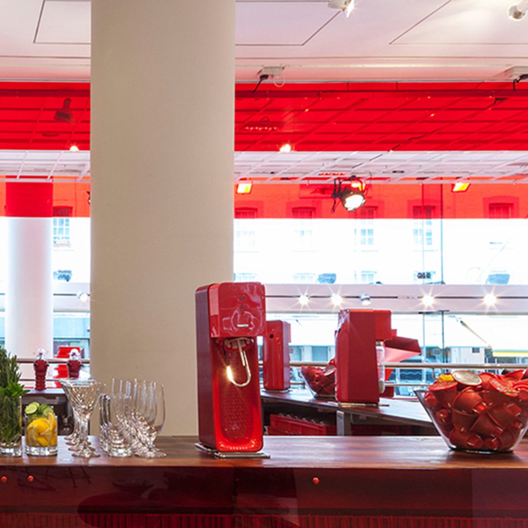 Red and white kitchen with countertop, coffee machine, and wine glasses