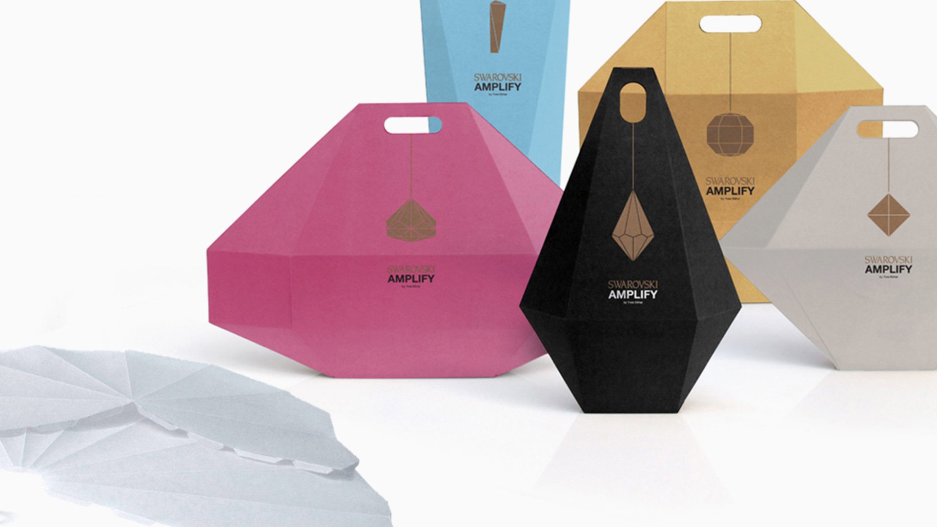 Three cardboard boxes in pink, black, and brown on a white surface