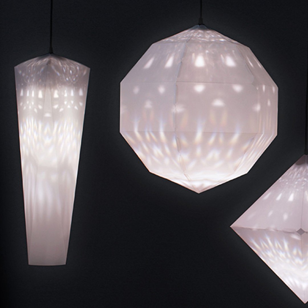 Three pendant lights in various shapes hang from a dark ceiling