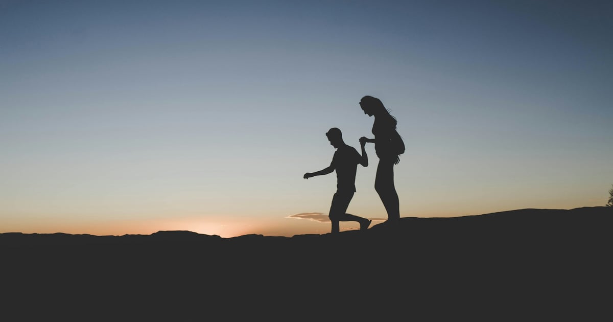 silhouette of man and woman walking on mountain