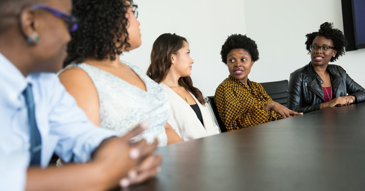 five people sitting at table and talking