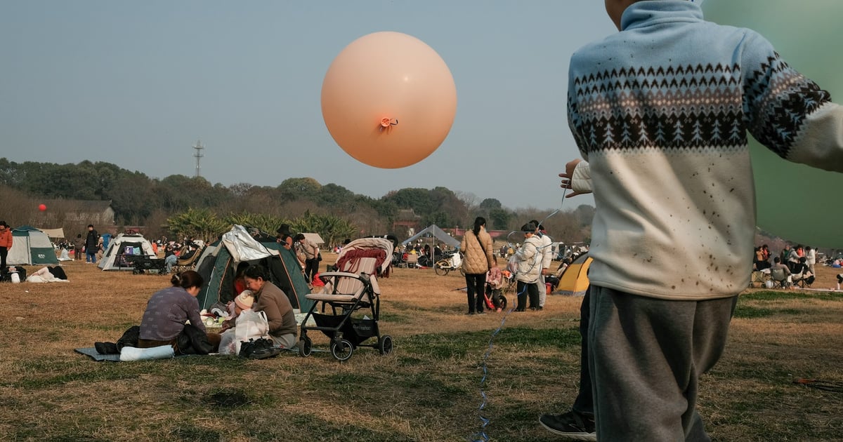 A boy holds a balloon at an outdoor gathering.