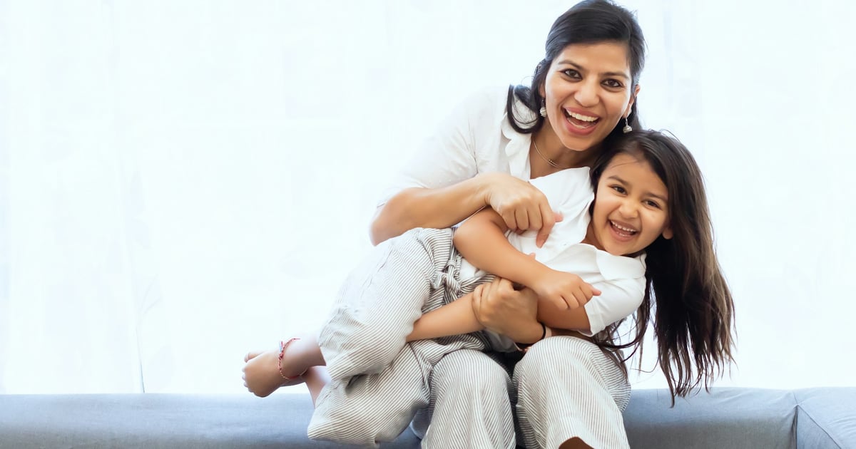 2 women sitting on gray couch