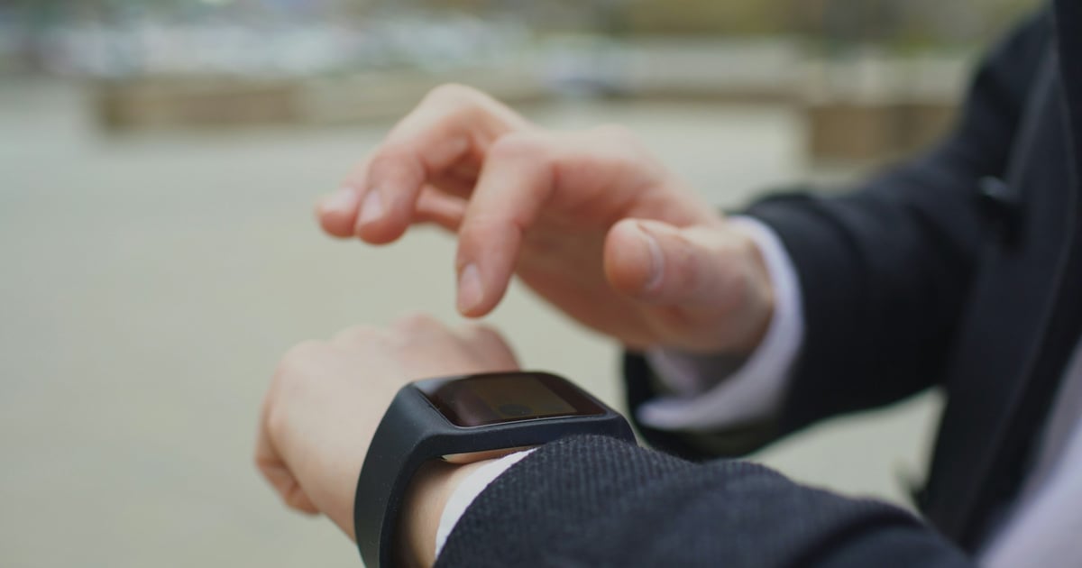 Man in suit checking smartwatch outdoors