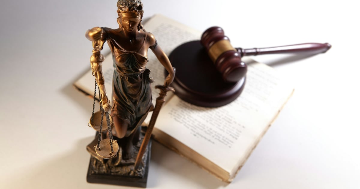 Statue of justice, gavel, and open book on table.