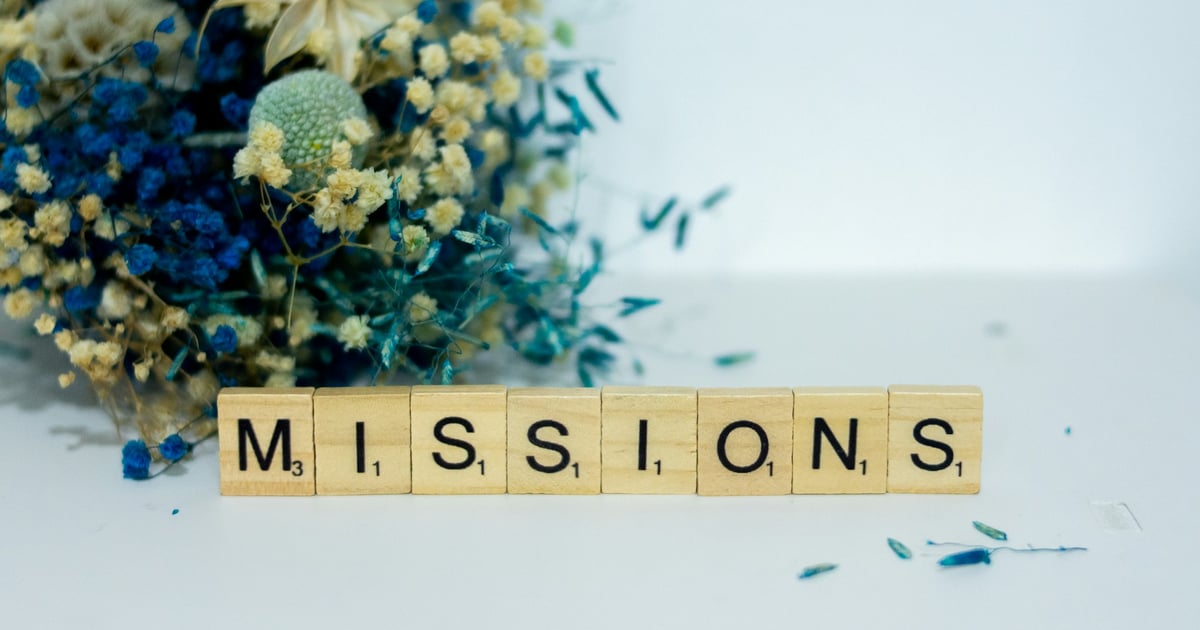 a scrabble type block spelling the word miss, sits next to a bouquet