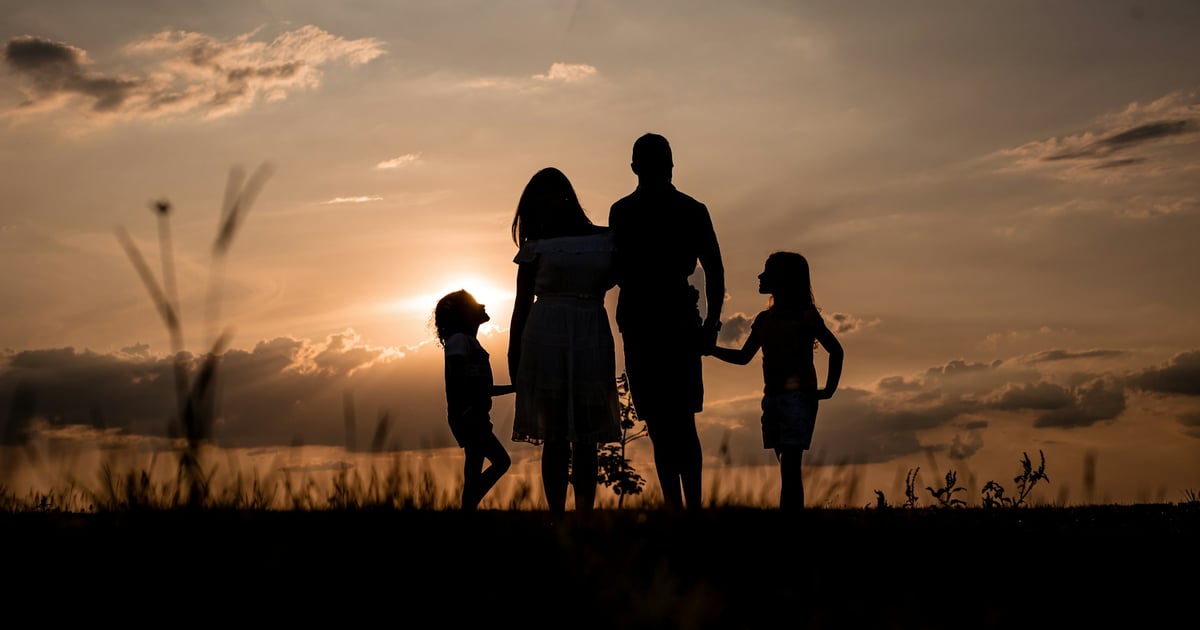 a family standing in a field at sunset
