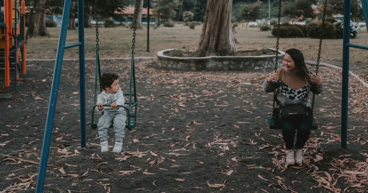 2 children sitting on swing during daytime