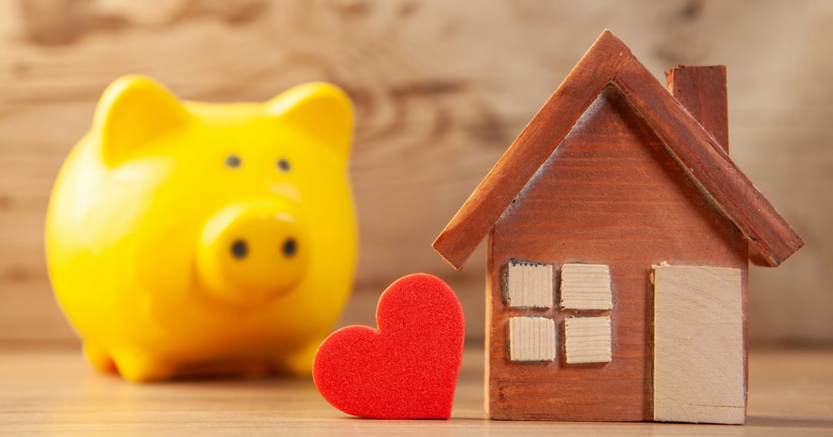 Yellow piggy bank with wooden house and red heart
