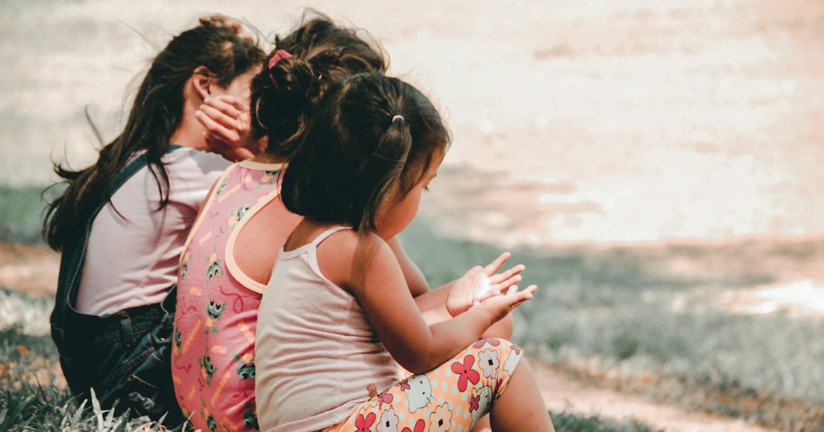 three children sitting on grass