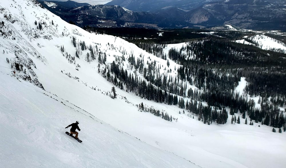 Andrew Cove snowboarding on a steep run at Big Sky, demonstrating advanced snowboard technique