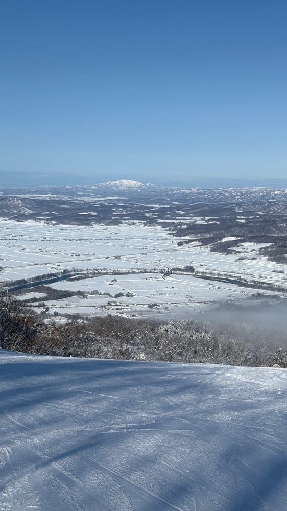 A breathtaking winter landscape with a snow-covered mountain range in the distance and a frozen lake or river in the foreground.
