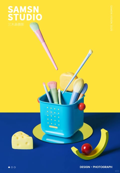 This image is a vibrant, high-contrast studio photograph with a playful, graphic aesthetic that blends photorealistic 3D rendering with a flat, poster-like composition. The visual style is characterized by a bold, saturated color palette dominated by a bright lemon-yellow background and a deep cobalt-blue foreground, creating a sharp, energetic split. The lighting is crisp and directional, likely from a single hard light source, casting well-defined, dark shadows that enhance the three-dimensional form of the objects while maintaining a clean, commercial look. The materials are rendered with a smooth, matte, almost plastic-like finish, giving the makeup brushes, container, and props a tactile, toy-like quality. Compositionally, the image uses a centered, symmetrical arrangement with a shallow depth of field, focusing on the central blue container and its contents, while the floating pink brush and other scattered elements add dynamic, diagonal lines. The shapes are a mix of soft, rounded organic forms (brush heads, cheese prop) and clean geometric lines (container, text), with sharp, crisp edges throughout. The overall mood is cheerful, modern, and whimsical, evoking a sense of playful creativity through its bright colors, simple forms, and clean, graphic presentation.