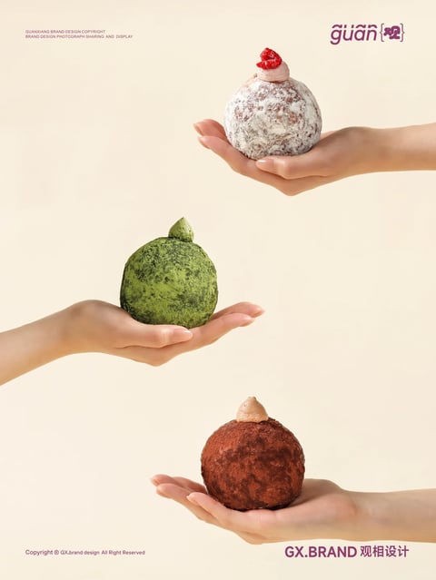 The image features three distinct, spherical pastries, each held in a different person's hand against a uniform, pale beige background. The top pastry is dusted with a fine white powder, has a textured, slightly cracked surface, and is topped with a small dollop of pink cream and a single red raspberry. The middle pastry is a vibrant, mossy green with a similar textured, powdered surface and is topped with a small, pointed green cream peak. The bottom pastry is a deep, rich brown with a fine, cocoa-like powder coating and is topped with a small, light brown cream peak. Each hand is positioned to cradle the pastry gently, emphasizing their round, organic forms and delicate nature. The overall style is realistic with a minimalist, clean aesthetic, focusing on the tactile qualities and appetizing appearance of the food items. The scale is intimate, suggesting a personal, hand-held serving size, and the context implies a high-end, artisanal dessert presentation.
