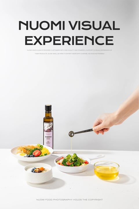 This is a clean, minimalist product photography image showcasing a bottle of organic flaxseed oil alongside prepared food, presented as a visual experience for a brand named 'Nuomi'. The composition is arranged on a smooth, light grey surface against a seamless, neutral white background, creating a bright and airy studio setting. The main subject is a dark amber glass bottle with a black screw cap and a white label featuring purple floral illustrations and Chinese characters, positioned slightly left of center. To its right, a hand enters the frame from the upper right, holding a black measuring spoon from which a thin, golden stream of oil is being drizzled into a white bowl containing a fresh salad of broccoli, tomatoes, and shrimp. In the foreground, there are two additional white bowls: one to the left containing a composed dish with noodles, corn, broccoli, a halved boiled egg, and tomatoes, and a smaller textured bowl in the front left with yogurt, granola, and berries. To the right, a clear glass bowl holds a pool of the golden oil. The visible text at the top reads 'NUOMI VISUAL EXPERIENCE' in large, bold, black sans-serif font, with smaller English text below describing the brand's mission to provide high-quality visual support. At the very bottom, faint text states 'NUOMI FOOD PHOTOGRAPHY HOLDS THE COPYRIGHT'. The lighting is soft and diffused, coming from the upper left, casting gentle, natural shadows to the right and creating a clean, commercial aesthetic with high-key brightness. The visual style is photorealistic with crisp focus, emphasizing the fresh textures of the food and the glossy, viscous quality of the oil. The color palette is dominated by neutral whites and greys, punctuated by the vibrant greens of the vegetables, the warm golden yellow of the oil and corn, and the deep amber of the bottle, creating a fresh, healthy, and premium atmosphere.