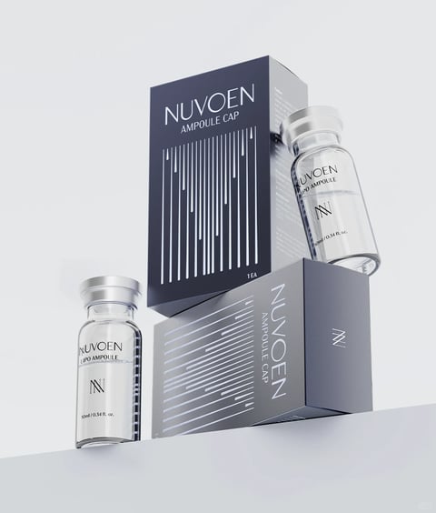 The image presents a minimalist, product-focused composition featuring two small, clear glass ampoules and their corresponding packaging boxes against a seamless, light gray background. The main subjects are arranged in a dynamic, slightly off-balance stack: one dark navy blue box stands upright, while a second box of the same design lies on its side, supporting one of the glass ampoules. A second ampoule sits independently to the left. The overall visual aesthetic is clean, modern, and photorealistic, with a strong emphasis on sleek, pharmaceutical or high-end skincare branding. The color language is restrained and sophisticated, dominated by a deep navy blue and cool silver-gray, with the clear glass and transparent liquid providing neutral, reflective accents. The palette is low in saturation, relying on contrast between the dark boxes and the light background. Lighting is soft and diffused, appearing to come from the upper left, casting gentle, elongated shadows that ground the objects and enhance their three-dimensional form without creating harsh highlights. Texture and material feel are rendered with precision: the boxes have a smooth, matte finish, the glass ampoules exhibit a polished, reflective quality with subtle distortions, and the metallic silver caps appear smooth and cool. The composition employs a deliberate, asymmetrical arrangement with a shallow depth of field, keeping all product elements in sharp focus while the background remains a soft, uniform field. Shape language is predominantly geometric and linear, characterized by the rectangular boxes, cylindrical ampoules, and the repeating vertical and diagonal line patterns printed on the packaging. The mood is clinical, premium, and serene, conveying a sense of scientific efficacy and understated luxury. Visible text is integral to the branding: the word 'NUVOEN' appears prominently in a clean, sans-serif, all-caps typeface on both boxes and ampoules. Below it, 'AMPOULE CAP' is printed on the boxes, and 'LIPO AMPOULE' appears on the glass vials. A stylized 'N' logo is also present. The text '10ml / 0.34 fl. oz.' indicates volume, and '1EA' denotes quantity. This text is rendered in white or dark gray, depending on the background, reinforcing the minimalist and informational design.
