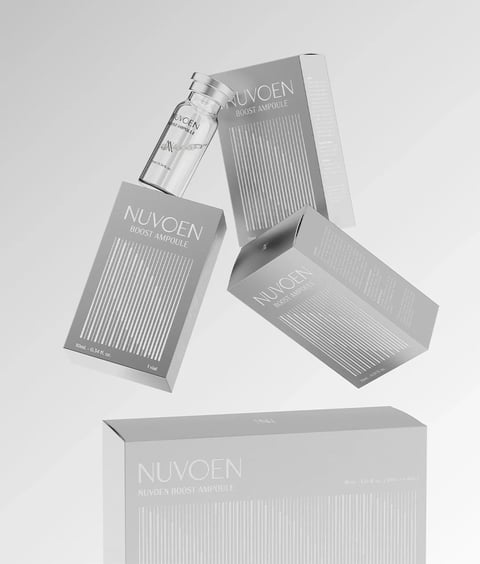 The image presents a minimalist, high-key product photography composition featuring skincare ampoules and their packaging, arranged in a dynamic, floating arrangement against a seamless, light gray background. The main subjects are three identical rectangular boxes and one small glass vial, all branded 'NUVOEN BOOST AMPOULE'. The composition is asymmetrical and layered, with one box standing vertically in the lower foreground, another angled diagonally in the mid-ground, and a third positioned higher and further back, creating a sense of depth and suspended motion. The glass vial, filled with a clear liquid, floats near the top-center, its silver cap catching the light. All text is in a clean, sans-serif font, primarily in white or a light gray, reading 'NUVOEN', 'BOOST AMPOULE', and volume information like '10mL - 0.34 fl. oz.' and '1 vial' on the individual boxes, and '40mL - 1.35 fl. oz. (10mL x 4 vials)' on the larger box at the bottom. The visual aesthetic is photorealistic 3D rendering, characterized by a monochromatic, cool-toned color language dominated by shades of silver, gray, and white, with very low saturation and subtle contrast. The lighting is soft, diffuse, and directional from the upper left, casting gentle, soft-edged shadows that enhance the three-dimensionality without creating harsh lines, conveying a clinical, premium, and serene mood. Texture and material are rendered with precision: the boxes have a smooth, matte silver finish with fine, vertically debossed or printed lines creating a tactile pattern, while the glass vial exhibits realistic transparency, refraction, and a polished metallic cap. The shape language is strictly geometric and clean, with sharp edges on the boxes and a cylindrical form for the vial, emphasizing precision and modernity. The overall atmosphere is one of sophisticated, scientific elegance, with a calm and weightless energy.