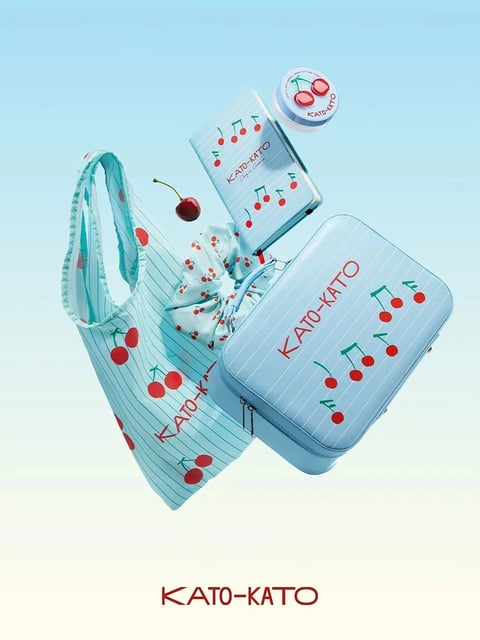 The image presents a cohesive, promotional-style composition featuring a collection of branded lifestyle and beauty accessories arranged in a dynamic, floating layout against a soft, gradient background. The primary subject is a set of items from the brand 'KATO-KATO,' unified by a playful cherry and musical note motif. The scene includes a light blue tote bag with thin white vertical stripes, a matching rectangular zippered pouch, a smaller rectangular box, a round compact case, and a fabric scrunchie, all featuring the same cherry and musical note pattern. The items are positioned as if suspended in mid-air, creating a sense of lightness and movement. The visual aesthetic is clean, modern, and illustrative with a photorealistic rendering style, emphasizing product appeal. The color language is dominated by a cool, pastel palette of light blue and white, punctuated by vibrant, saturated red cherries and dark green stems and musical notes, creating a fresh, high-contrast look. The lighting is soft and diffused, appearing to come from the front and slightly above, casting gentle shadows that give the objects volume and a sense of floating without harshness. Texture and material feel are rendered to suggest smooth, matte surfaces for the pouch and box, a soft, woven fabric for the tote and scrunchie, and a glossy finish on the cherry illustrations and the round compact. The composition uses a dynamic, asymmetrical arrangement with overlapping elements to create depth and visual interest, guiding the eye across the various products. Shape language combines the soft, organic curves of the cherries, scrunchie, and bag handles with the clean, geometric rectangles and rounded corners of the pouch and box. The overall mood is cheerful, youthful, and fresh, evoking a sense of playful elegance. Visible text includes the brand name 'KATO-KATO' printed in a bold, sans-serif, dark red font on the tote bag, the rectangular pouch, the smaller box, and the round compact, as well as a larger version at the bottom center of the image. The text 'Cherry on the...' is partially visible in a smaller script font on the smaller box. The text serves as a clear branding element, reinforcing product identity within the cohesive design theme.